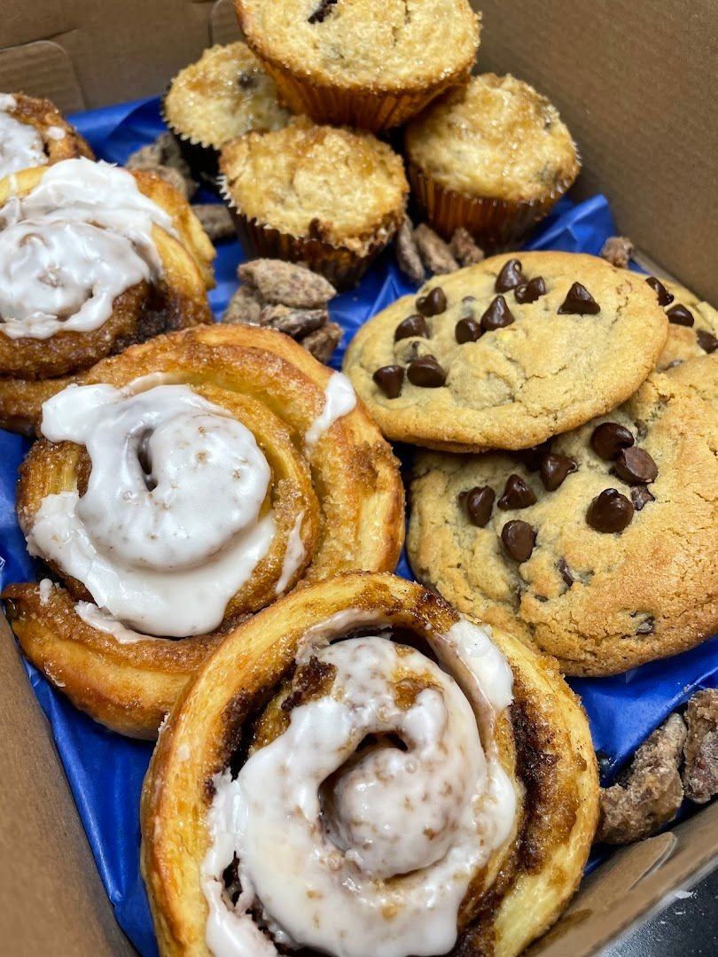 A box of cinnamon rolls, muffins and chocolate chip cookies